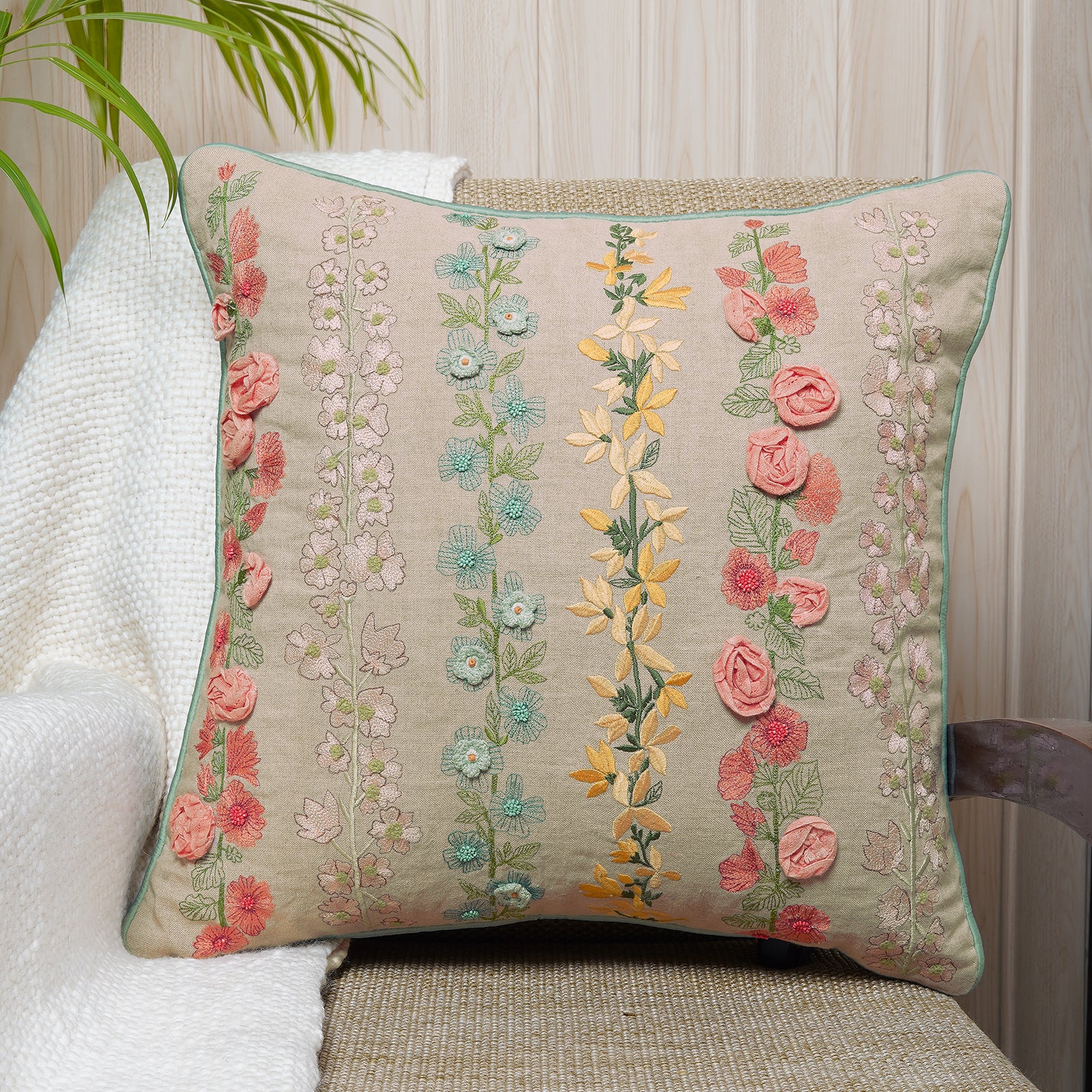 Decorative embroidered floral cushion in multicolor on a beige fabric.